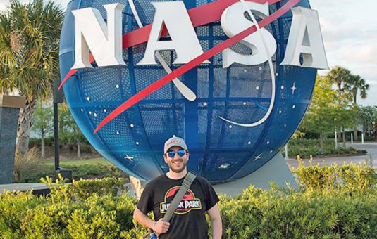 J.P. Burke, Clark alum and NASA employee, standing in front of NASA sign