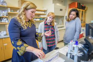 Karen Frey showing two female students samples in lab