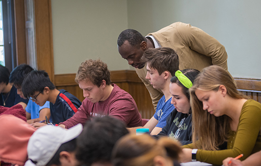 world Economics class with professor looking over students work